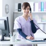 dental assistant in scrubs answers the phone