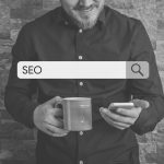 man on phone with search box reading SEO black and white image
