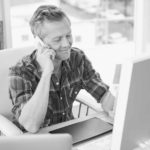 A man talking on the phone at his desk - Golden Proportions Marketing